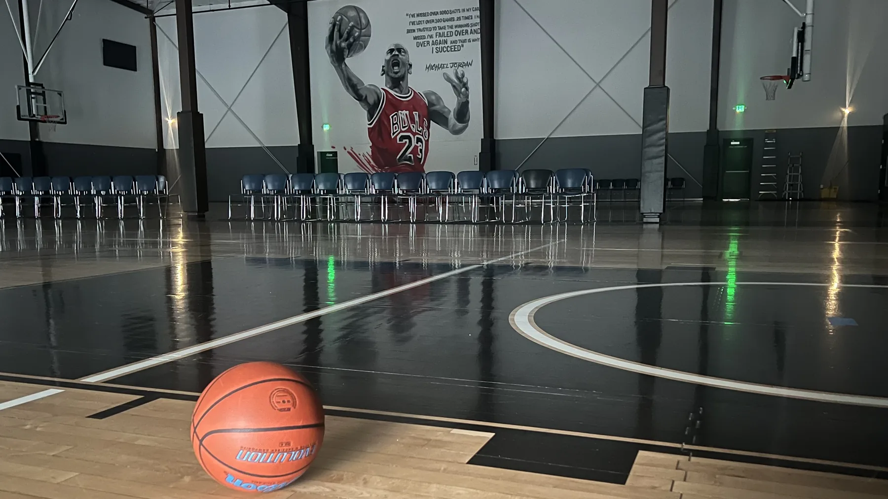 The empty main court at Training Zone in Herriman, Utah, set with rows of chairs in front of the mural